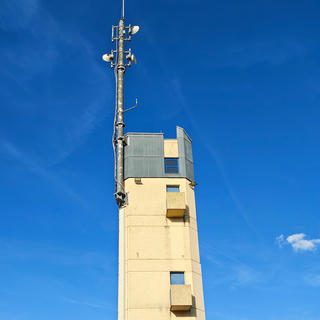 A photo of a mysterious "radio" tower against a blue sky streaked with wisps of clouds.